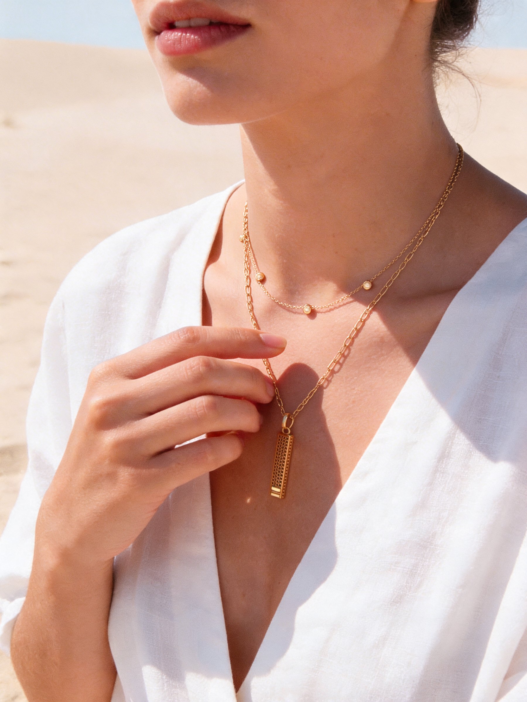 Woman wearing the BELONG pendant on a gold chain